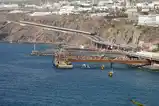 A rocky coastline on Tenerife where a highway on a viaduct, a covered road along the cliff and industrial piers with a yellow walkway all come together above deep blue water